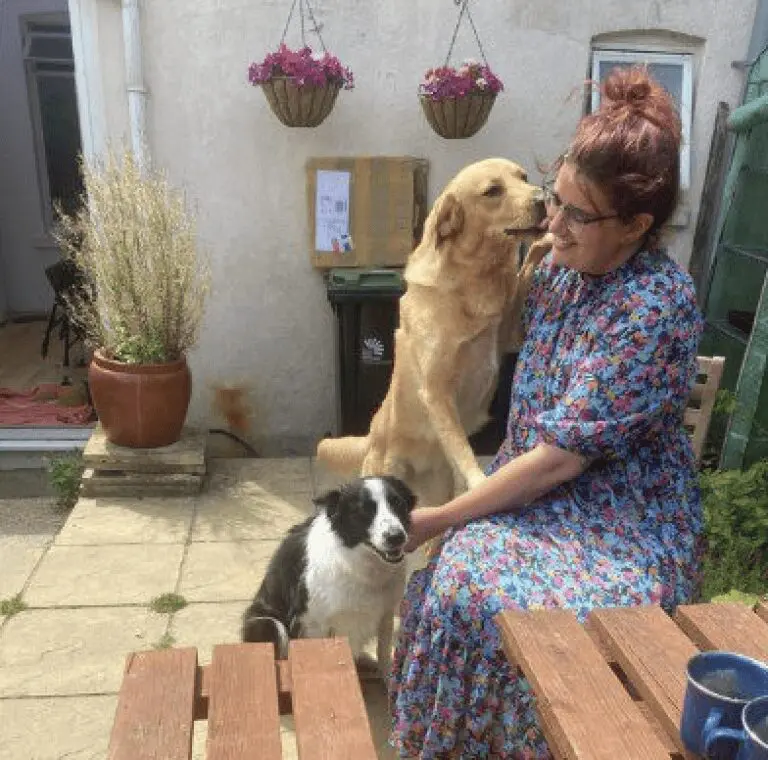 A photo of Paws2Rescue team member Rose smiling as a dog jumps up to lick her face